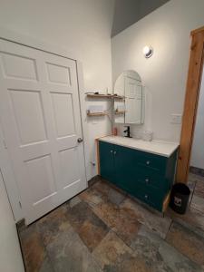 a bathroom with a green cabinet and a white door at Cozy Container in Soldotna +16 photos