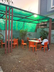 two people sitting at tables and chairs under a tent at Oasis Fun Villa - Pet Friendly Cafe in Indore