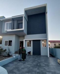 two people standing in front of a house with a dog at Oasis Fun Villa - Pet Friendly Cafe in Indore