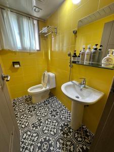 a yellow bathroom with a sink and a toilet at Osoha guest house in Samcheok