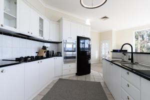 a kitchen with white cabinets and a black refrigerator at Tamar River Hideaway in Legana