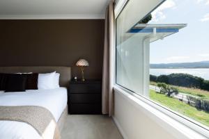 a bedroom with a large window with a view of the water at Tamar River Hideaway in Legana