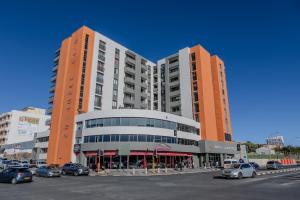 two tall buildings with cars parked in a parking lot at The Stay Edit Windhoek in Windhoek
