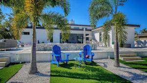 two blue chairs and palm trees in front of a house at Stay & Play Sarasota in Sarasota +32 photos