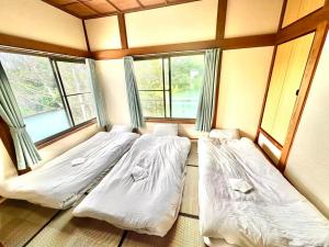two beds in a room with two windows at 古民家松 in Isumi