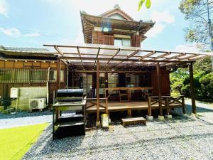 a house with a wooden deck and a grill at 古民家松 in Isumi