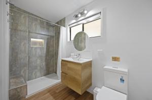 a bathroom with a shower and a sink and a toilet at Agnes Bush Cabins in Agnes Water +14 photos