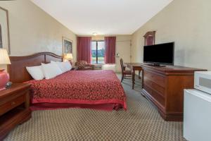 a hotel room with a bed and a flat screen tv at Days Inn & Suites by Wyndham Dayton North in Dayton