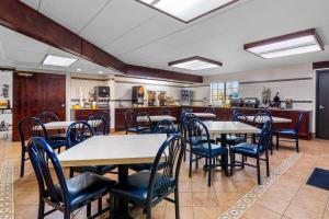 a restaurant with tables and chairs and a kitchen at Days Inn by Wyndham Minot in Minot
