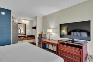a bedroom with a bed and a flat screen tv at Baymont by Wyndham Warner Robins in Warner Robins