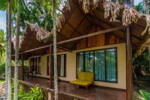 a house in the woods with a yellow chair on a porch at Munjoh Ocean Resort - Private Beachfront Luxury Retreat in Havelock in Havelock Island +37 photos
