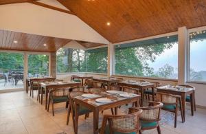 a restaurant with wooden tables and chairs and windows at The Row House Kasauli in Kasauli