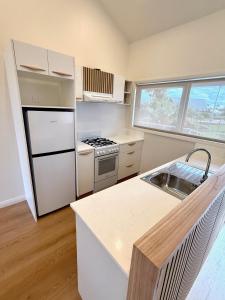 a kitchen with a white refrigerator and a sink at Fletcher Christian Apartments - Manava Suites in Burnt Pine