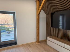 a living room with a flat screen tv and a window at Apartament Wypoczynkowy Centrum in Tuchola +2 photos