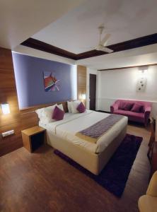 a bedroom with a large bed and a pink couch at Westwood Riverside in Munnar