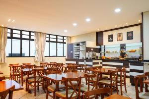 a restaurant with wooden tables and chairs and a kitchen at Hotel Brasil in Penha