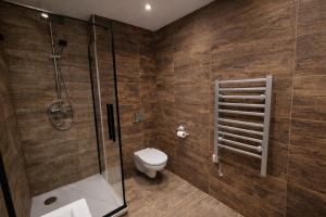 a bathroom with a toilet and a glass shower at Apartmány Bojnický Vínny Dom in Bojnice +8 photos