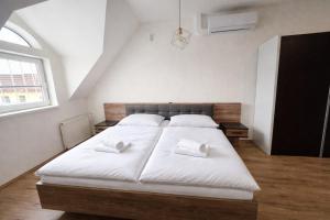 a bedroom with a large white bed with two white pillows at Apartmány Bojnický Vínny Dom in Bojnice
