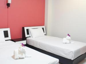 two beds in a room with white and red walls at Nan Treasure Hotel in Ban Hua Wiang Nua