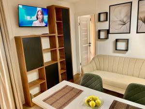 a living room with a couch and a tv on a wall at The Forest Retreat in Mihăeşti