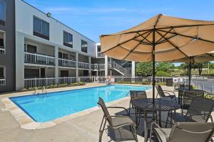 a pool with tables and chairs and an umbrella at Quality Inn Duluth - Atlanta Northeast in Duluth