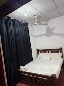 a bedroom with a bed with a black curtain at Ela addara Home stay in Lukasgoda
