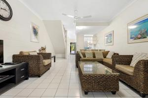 a living room with couches and a clock on the wall at Mango Tree Holiday Apartments in Port Douglas