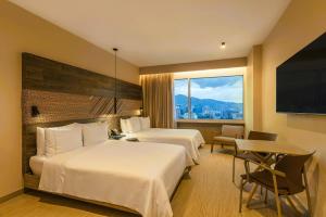 a hotel room with two beds and a large window at V Grand Hotel, a member of Radisson Individuals in Medellín