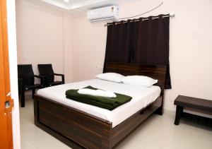 a bedroom with a bed with white sheets and chairs at Hotel Ram Way in Visakhapatnam +17 photos