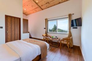 a bedroom with a bed and a desk and a window at Kaafal Cottage in Mukteshwar