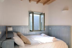 a bed with pillows in a room with a window at Aegea Blue Cycladic Resort in Zorgos 