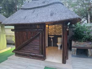 a small bathroom with a toilet and a thatch roof at CLP Lodge in Bela-Bela