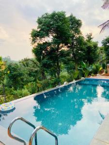 a blue swimming pool with trees in the background at Mercure Resort Wayanad in Mananthavady