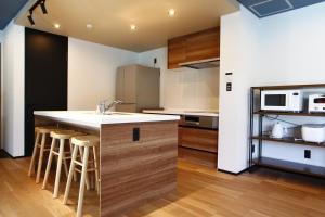 a kitchen with a sink and a counter with stools at Nord SUR in Ichinomiya