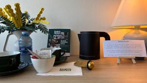 a table with a vase of flowers and a lamp at Logis Hôtel & Restaurant - Le Saint-Louis in La Suze-sur-Sarthe