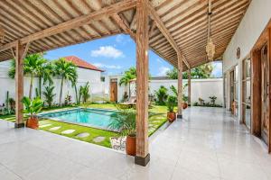 an outdoor patio with a swimming pool and a wooden pergola at Simple & Magical Villas PRAYA in Seminyak