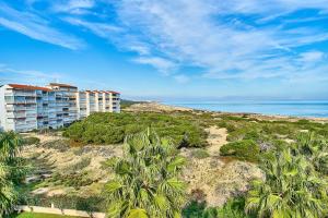 a building on a hill with palm trees and the ocean at Espanhouse Pinada Beach in La Marquesa
