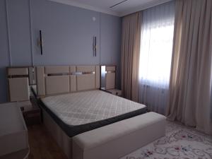 a bedroom with a bed and a window at Самал 3 in Shymkent