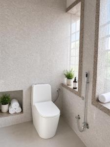 a white bathroom with a toilet and a window at Garh Harsolav in Harsolāv