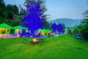 a group of tables and chairs in a yard at night at The Himalayan Swiss Cottage with Bonfire, Manali - A Riverside Retreat in Manāli