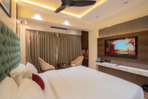 a hotel room with a bed and a flat screen tv at Mosaic Go Star Grand in Navi Mumbai