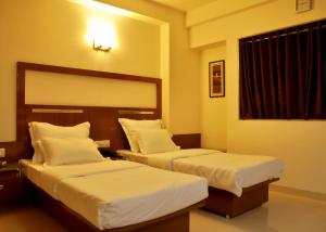 een hotelkamer met twee bedden en een raam bij Hotel Happiness in Surat +16 foto's