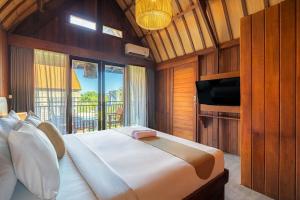 a bedroom with a bed with a television and a balcony at Cove Dadeka in Canggu +21 photos