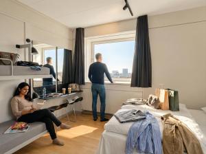 a man standing in a bedroom looking out the window at Danhostel Copenhagen City & Apartments in Copenhagen