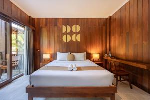 a bedroom with a large bed with wooden walls at Cove Dadeka in Canggu