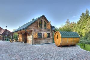 ein großes Holzhaus mit einem großen Fass davor in der Unterkunft Świerkowe Zacisze Domki in Budzów
