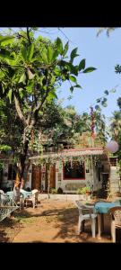 a building with benches in front of a tree at Bageecha B&B - K S H I T H I in Alībāg