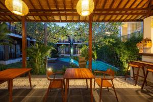 a patio with tables and chairs and a pool at Cove Dadeka in Canggu