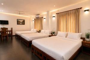 a hotel room with two beds and a table at The Regatta Landing in Alleppey