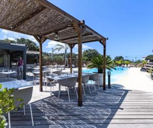 a restaurant with tables and chairs next to a pool at Cottage PARKS ESCAPADE COLOMBA in Olmeto